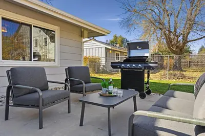 a barbecue on a patio with chairs and a grill at Moody Modern Getaway Walk to CSU and City Park in Fort Collins