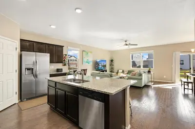an open kitchen and living room with a stainless steel refrigerator at Windshire Retreat with Pool, Garage and Pet-Friendly in Windsor