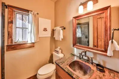 a bathroom with a sink and a toilet and a mirror at Barnwood Beauty at Grand Elk- Pet Friendly- Hot Tub Private Golf Ski Games in Granby