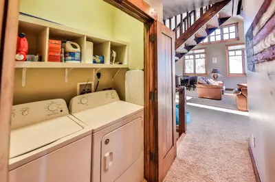 a kitchen with a washer and dryer and a living room at Barnwood Beauty at Grand Elk- Pet Friendly- Hot Tub Private Golf Ski Games in Granby
