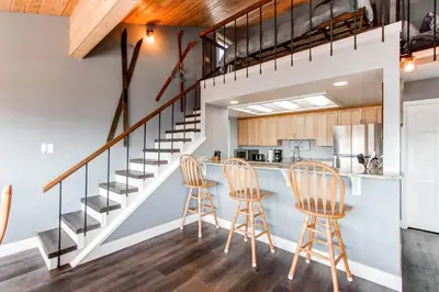 a kitchen with two bar stools and a staircase at 10-Person HotTub, ViewHouse, Steps to Trail, Close to Ski Resorts, FirePit in Silverthorne