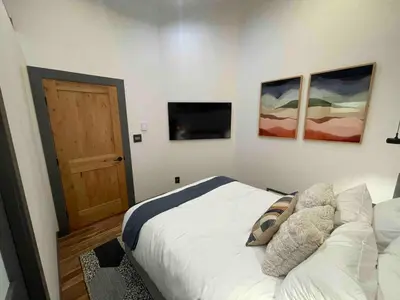a bedroom with a bed and a television and a door at Blue Owl - Tree House Views! Couples Getaway! in Idaho Springs