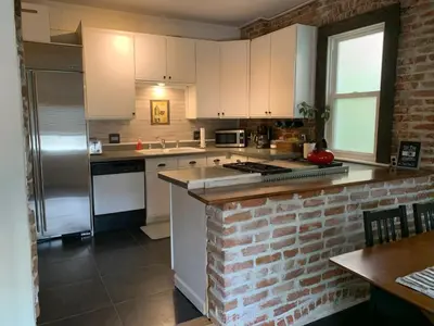 a kitchen with white cabinets and a brick wall at Blue Ox Charming 2 Bedroom Triplex - S Broadway in Denver