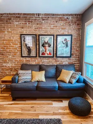 a living room with a blue couch against a brick wall at Blue Ox Charming 2 Bedroom Triplex - S Broadway in Denver