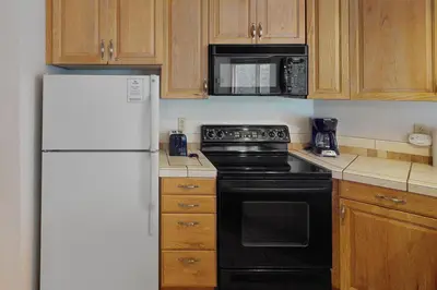 a kitchen with a black stove and a white refrigerator at Iron Horse Resort 5064 in Winter Park