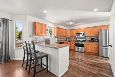 a kitchen with wooden cabinets and a island with bar stools at Spacious SIX Bedroom, Great Location in Longmont