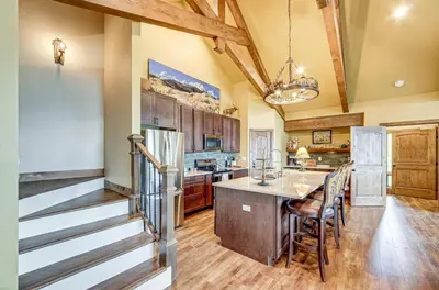 a kitchen with a staircase leading up to a dining room at New Mountain Home, Amazing Unobstructed Lake & Mountain Views, Hot Tub, Close to Town! in Grand Lake
