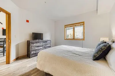 a bedroom with a bed and a dresser with a television at 5094 Gateway condo in Keystone