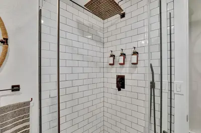 a white tiled shower with three lights on it at Modern Comfort in Historic Denver in Denver