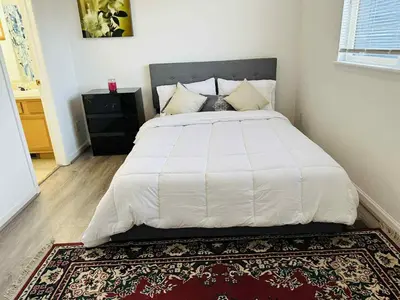 a bedroom with a large white bed with a rug at Cozy near airport vacation home Brighton in Brighton