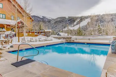 a swimming pool with snow covered mountains in the background at Buffalo Lodge 8372 in Keystone