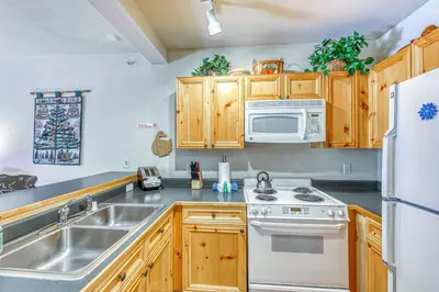 a kitchen with wooden cabinets and a sink and a refrigerator at Tenderfoot Lodge 2664 in Keystone