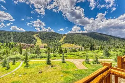 a view from the deck of a house with a field and mountains at Tenderfoot Lodge 2664 in Keystone