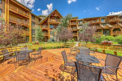 a deck with tables and chairs in front of a building at Tenderfoot Lodge 2664 in Keystone
