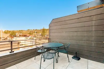 a patio with a table and chairs on a balcony at Stylish Grand Lake Retreat - King Bed - Walk to Lake in Grand Lake