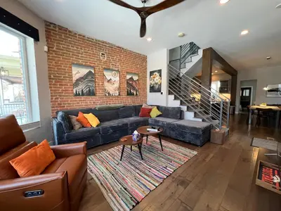a living room with a couch and a brick wall at UPTOWN CASTLE - CITY VIEWS - THEATER & CONVENTION DISTRICT! in Denver