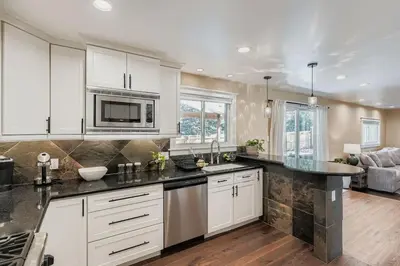 a kitchen with white cabinets and black counter tops at Bright and Cozy Ranch Style House Centennial in Centennial