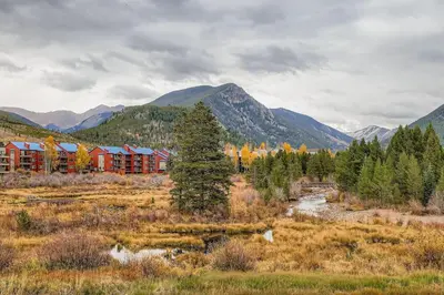 a building in a field with mountains in the background at Snowdance C304 condo in Keystone