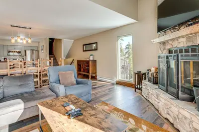 a living room with a stone fireplace and a table at Multi-Level Haven 3 Mi to Lake Dillon in Silverthorne