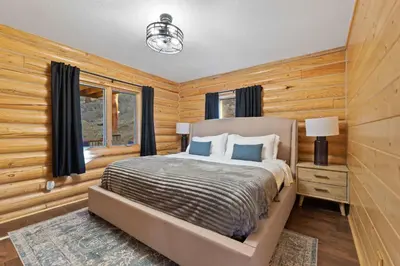 a bedroom with wooden walls and a bed with blue pillows at Private Hilltop Panoramic Mountain View - Family in Estes Park