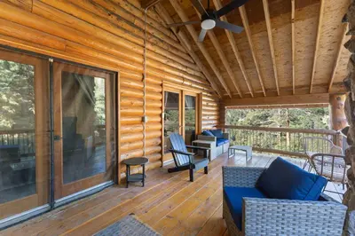 a screened in porch with chairs and a ceiling fan at Private Hilltop Panoramic Mountain View - Family in Estes Park