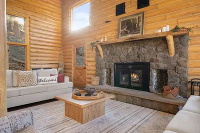 a living room with a fireplace in a log cabin at Private Hilltop Panoramic Mountain View - Family in Estes Park
