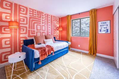 a bedroom with orange walls and a blue bed at Movie Theater and Mini Golf with 2 King Beds in Westminster