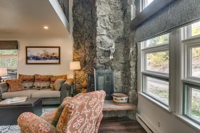 a living room with a stone wall at The Mountain Chalet - Free Ski Shuttle to Lifts! in Winter Park