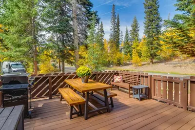a wooden deck with a table and benches and a grill at The Mountain Chalet - Free Ski Shuttle to Lifts! in Winter Park