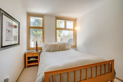a bedroom with a large bed and two windows at Mtn-View Deck, Workspace! Walkable Frisco Condo in Frisco