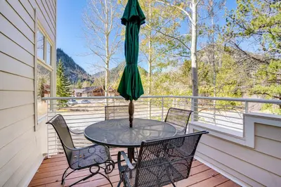 a table and chairs on a porch with an umbrella at Mtn-View Deck, Workspace! Walkable Frisco Condo in Frisco