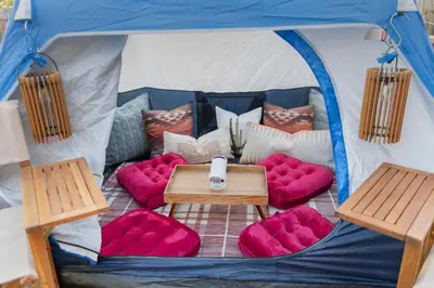 a blue and white tent with red pillows and a table at Game Room Paradise, Firepit & Outdoor Movies in Arvada