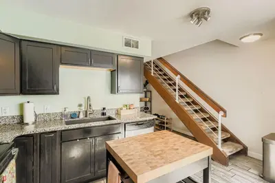 a kitchen with black cabinets and a spiral staircase at The Santa Fe Spot Walk to Eats, Drinks and Fun in Denver
