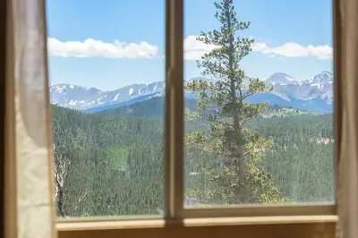 a window with a view of a tree and mountains at Skyline Lodge in Idaho Springs