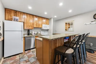 a kitchen with wooden cabinets and a white refrigerator at Mountain Charmer Steps to Main St and Trails in Frisco
