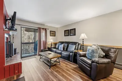 a living room with a leather couch and a tv at Mountain Charmer Steps to Main St and Trails in Frisco