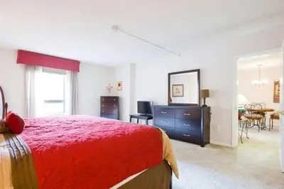 a bedroom with a red bed and a dining room at Brooks Tower Downtown Denver Furnished Apartment in Denver