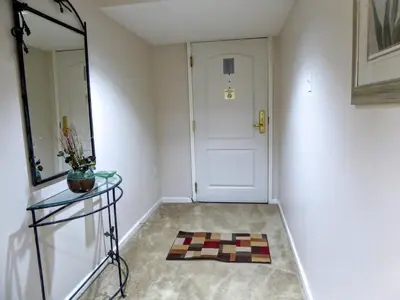 a hallway with a mirror and a door and a rug at Brooks Tower Downtown Denver Furnished Apartment in Denver