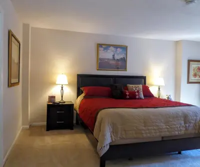 a bedroom with a bed with red sheets and two lamps at Brooks Tower Downtown Denver Furnished Apartment in Denver