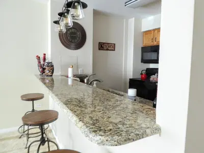 a kitchen with a granite counter top and stools at Brooks Tower Downtown Denver Furnished Apartment in Denver