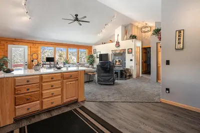 a kitchen with wooden cabinets and a living room at Cozy Mountain Cabin with Stunning Views in Idaho Springs