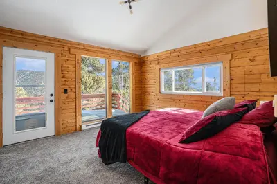a bedroom with a red bed in a room with wooden walls at Cozy Mountain Cabin with Stunning Views in Idaho Springs