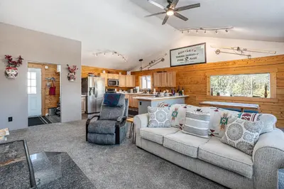 a living room with a couch and a kitchen at Cozy Mountain Cabin with Stunning Views in Idaho Springs