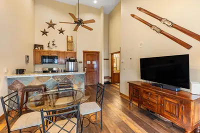 a living room with a glass table and a flat screen tv at Arapahoe Lodge 8137 in Keystone
