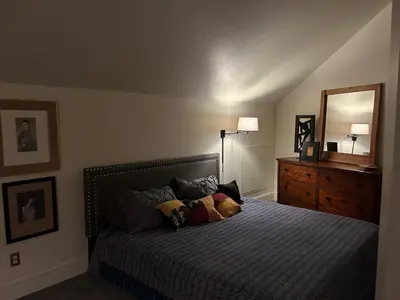 a bedroom with a bed and a dresser and a mirror at Innkeeper Suite at The Currier Inn in Greeley