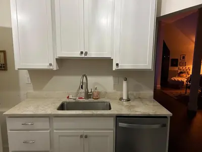 a kitchen with white cabinets and a sink at Innkeeper Suite at The Currier Inn in Greeley