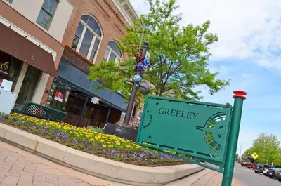 a green street sign in front of a building at Cute 1 Bdrm Bungalow - New Flooring! in Greeley