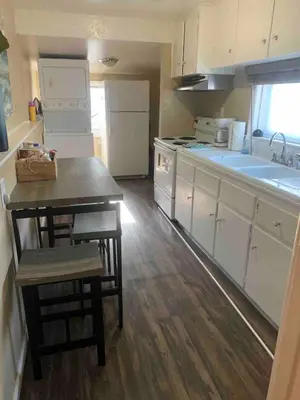 a kitchen with white cabinets and a table and a sink at Cute 1 Bdrm Bungalow - New Flooring! in Greeley