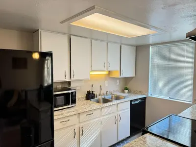 a kitchen with white cabinets and a black refrigerator at The Cozy Condo - Your Home Base near all amenities in Aurora