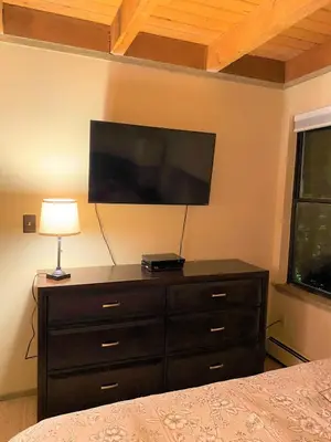 a bedroom with a dresser with a flat screen tv at Summit County Wildernest Condo in Silverthorne